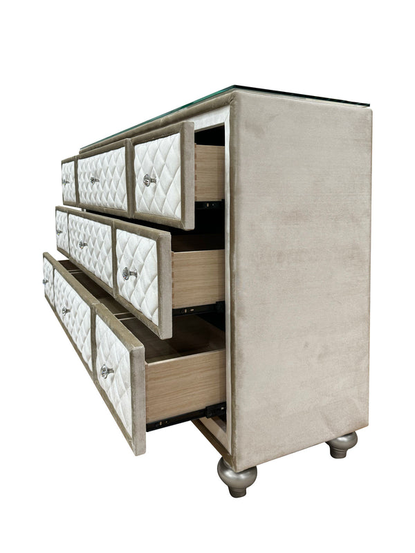 Sonya Beige Velvet Upholstered Traditional Style Dresser A modern 5-drawer dresser with a champagne beige velvet upholstered frame, diamond-quilted drawer fronts, silver knobs, and a clear glass top, shown with two drawers open on a white background.