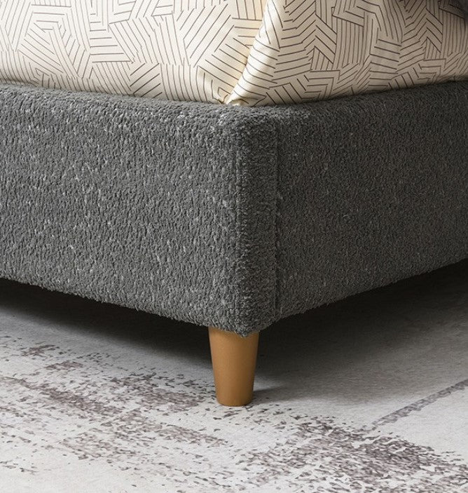 Stivan Bed Fully Upholstered Gray Boucle Fabric Gray upholstered bed in a bedroom with decor elements.