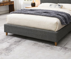 Stivan Bed Fully Upholstered Gray Boucle Fabric Gray upholstered bed with white bedding and a gray blanket in a bedroom setting.