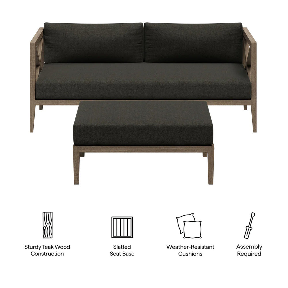 Sunshore Flint Gray Loveseat and Ottoman Outdoor Set Outdoor patio set with cushions on a stone patio, surrounded by flowers and a scenic view.