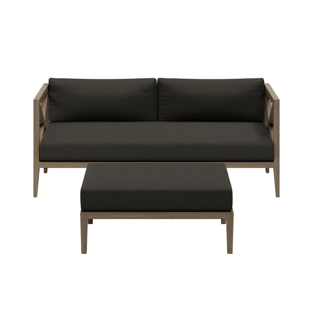 Sunshore Flint Gray Loveseat and Ottoman Outdoor Set Outdoor patio set with cushions on a stone patio, surrounded by flowers and a scenic view.