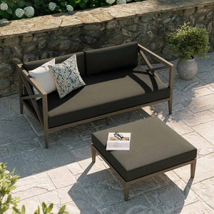 Sunshore Flint Gray Loveseat and Ottoman Outdoor Set Outdoor patio set with a sofa and ottoman on a stone patio.