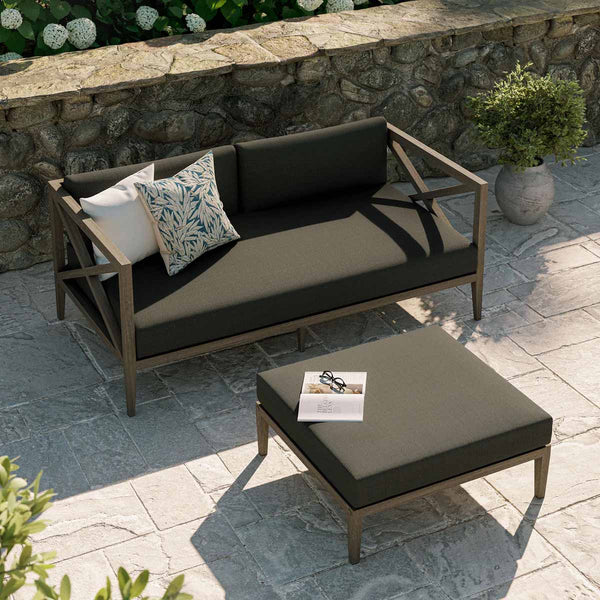 Sunshore Flint Gray Loveseat and Ottoman Outdoor Set Outdoor patio set with a sofa and ottoman on a stone patio.