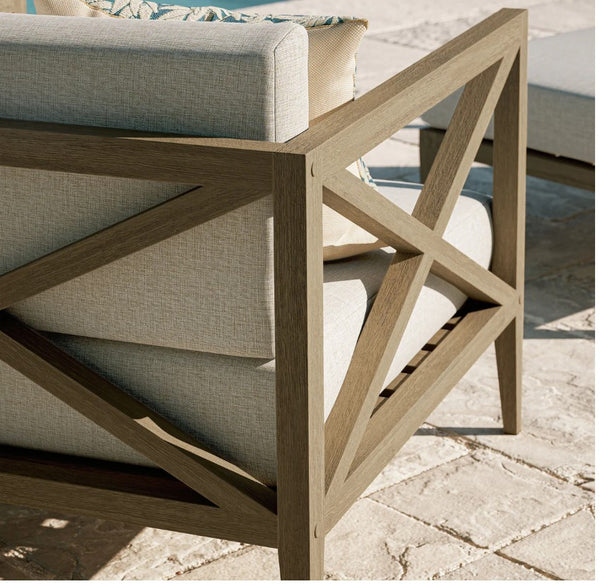 Sunshore Pebble Outdoor Armchair Outdoor furniture set with wooden frame and gray cushions on a stone patio.