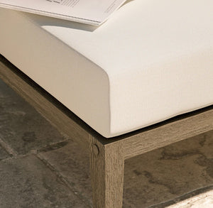 Sunshore Weather Gray Outdoor Ottoman Close-up of a wooden bench with a white cushion on a stone floor.