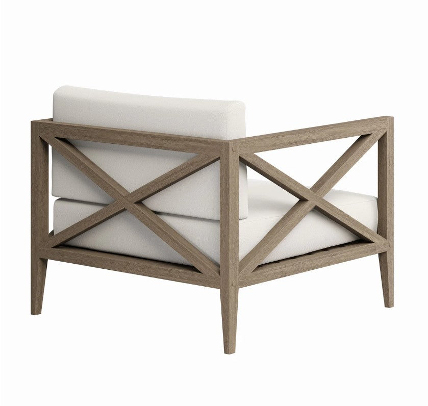Sunshore Weathered Gray Outdoor Armchair Outdoor chair with white cushions and a patterned pillow on a stone patio.