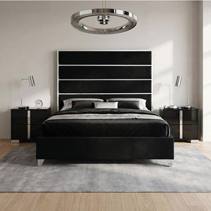 Sysko Glam Black Silver Fully Upholstered Bed A modern black bed frame with a tall segmented headboard, styled in a bedroom with a gray rug, light wood floor, black nightstands, silver lamps, and a circular silver ceiling light.