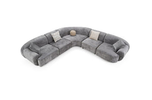 Tiarra Corner Sectional Sofa Fabric Gray A curved modular sectional sofa upholstered in textured gray fabric, featuring four light beige throw pillows and a small round beige accent pillow, shown on a plain white background.