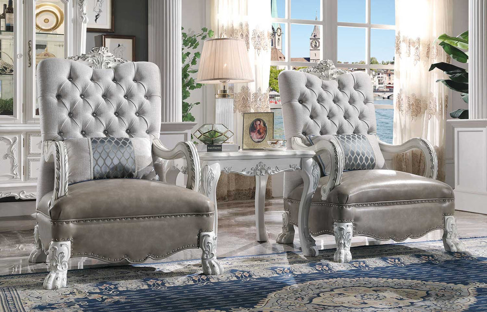 Traditional Style Armchair Bone White Dresden Collection A pair of elegant tufted armchairs in a light gray velvet fabric with ornate white carved frames, set in a luxurious room with a matching side table and blue patterned rug.