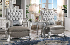 Traditional Style Armchair Bone White Dresden Collection A pair of elegant tufted armchairs in a light gray velvet fabric with ornate white carved frames, set in a luxurious room with a matching side table and blue patterned rug.