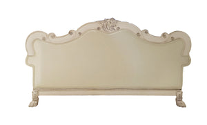 Traditional Style Sofa Bone White Dresden Collection An ornate upholstered headboard with a distressed cream finish, featuring carved details and scrollwork on the frame and top crest.