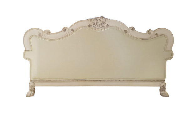 Traditional Style Sofa Bone White Dresden Collection An ornate upholstered headboard with a distressed cream finish, featuring carved details and scrollwork on the frame and top crest.