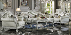 Traditional Style Sofa Bone White Dresden Collection An ornate white and silver carved sofa set with matching armchair, coffee table, and rug displayed in a luxurious decorated living room.