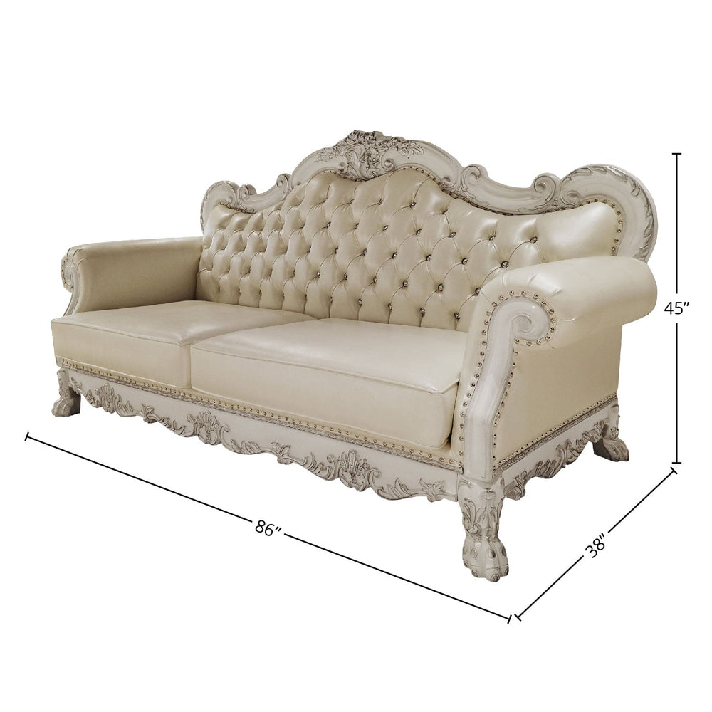 Traditional Style Sofa Bone White Dresden Collection An ornate white and silver carved sofa set with matching armchair, coffee table, and rug displayed in a luxurious decorated living room.