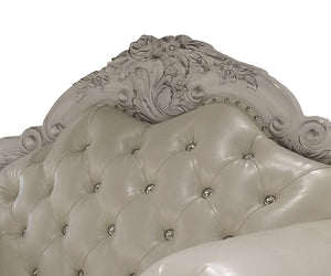 Traditional Style Sofa Bone White Dresden Collection Close-up of an ornate upholstered headboard with a carved floral crest, tufted button detailing, and small metallic nailhead accents on a white background.