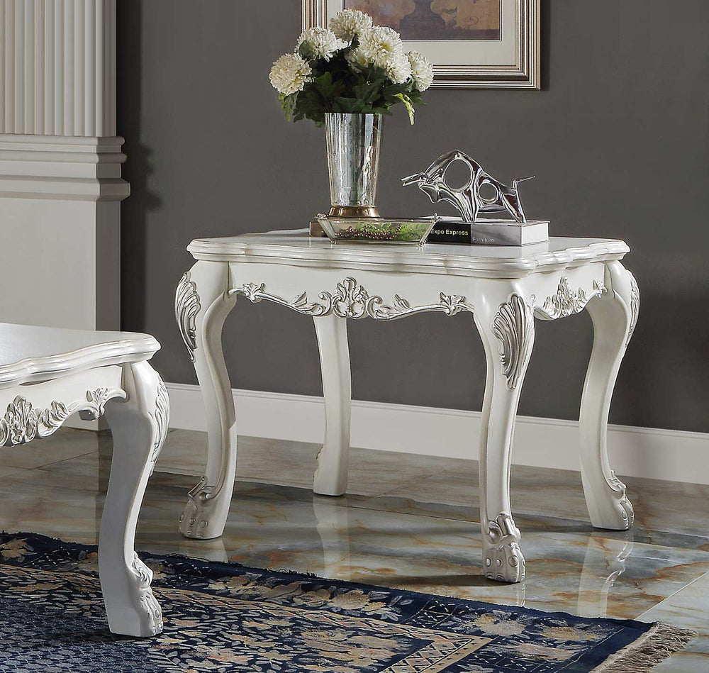 Traditional Style End Table Bone White Dresden Collection An ornate white carved console table with cabriole legs and floral scroll details, styled with a vase of white flowers and books in a room with a gray wall and marble floor.