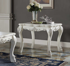 Traditional Style End Table Bone White Dresden Collection An ornate white carved console table with cabriole legs and floral scroll details, styled with a vase of white flowers and books in a room with a gray wall and marble floor.