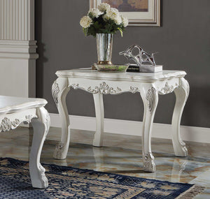 Traditional Style End Table Bone White Dresden Collection An ornate white carved console table with cabriole legs and floral scroll details, styled with a vase of white flowers and books in a room with a gray wall and marble floor.