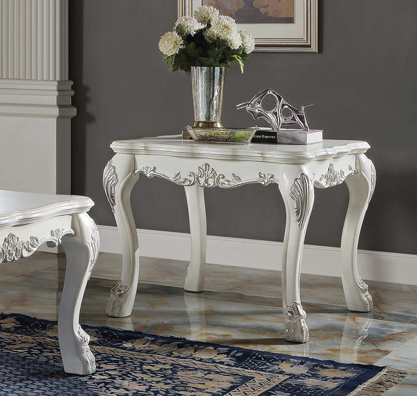 Traditional Style End Table Bone White Dresden Collection An ornate white carved console table with cabriole legs and floral scroll details, styled with a vase of white flowers and books in a room with a gray wall and marble floor.
