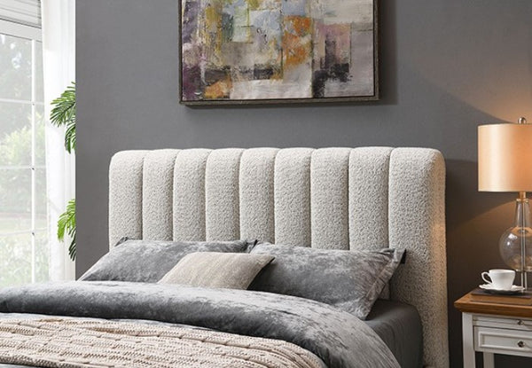 Traver Padded Vertical Channel Headboard Bed White Gray upholstered bed with matching bedding in a bedroom setting.
