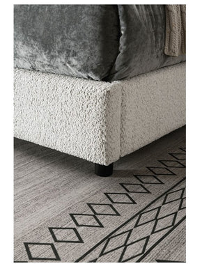 Traver Padded Vertical Channel Headboard Bed White Close-up of a textured sofa corner with a geometric patterned rug on the floor.