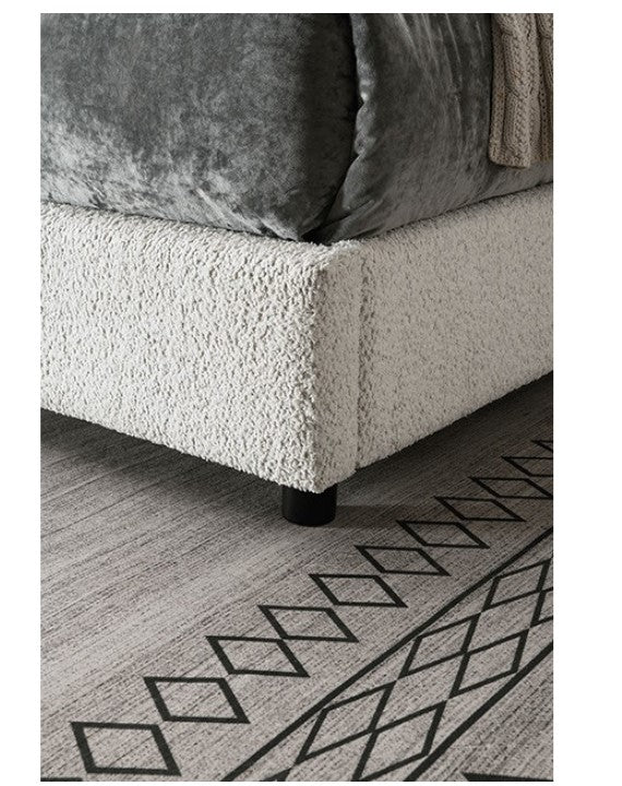 Traver Padded Vertical Channel Headboard Bed White Close-up of a textured sofa corner with a geometric patterned rug on the floor.