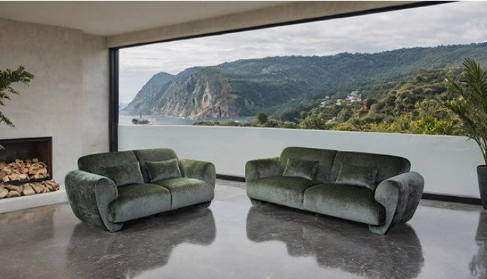 Travus Olive Green Chenille Loveseat Green velvet sofa in a room with a large window showing a mountainous landscape.