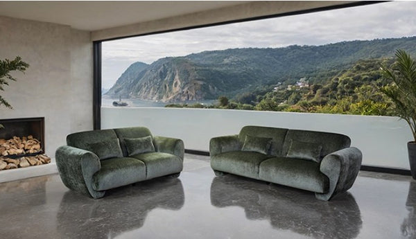 Travus Olive Green Chenille Sofa Two green sofas in a modern living room with a scenic view of mountains and water.