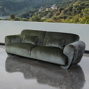 Travus Olive Green Chenille Sofa Green sofa on a reflective surface with a scenic background