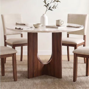 Unberto Two Tone Round Dining Table & Chairs Set A round dining table with a white marble-look top and a dark wood pedestal base, surrounded by four upholstered dining chairs in a bright neutral dining room.