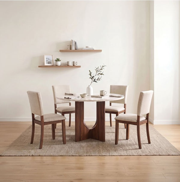 Unberto Two Tone Round Dining Table & Chairs Set A 5-piece dining set featuring a round white marble-top table with a dark wood pedestal base and four matching chairs with cream upholstery, styled on a woven rug against a warm beige wall.