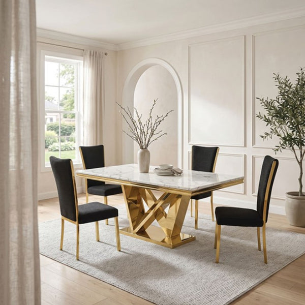 Valdi Gold White Sintered Stone Top Dining Table A modern dining room set featuring a rectangular marble-top table with a gold geometric base and four black upholstered chairs with gold legs, styled in a bright, elegant room with cream walls and wood floors.