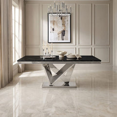 Valdi Silver Black Sintered Stone Top Dining Table A modern rectangular dining table with a glossy black top and a polished chrome geometric X-shaped pedestal base, styled in a bright, elegant dining room with beige paneled walls and marble floors.