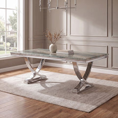 Valdi Silver Gray Sintered Stone Top V-Style Pedestal Dining Table A rectangular dining table with a polished silver chrome base and a gray marble-patterned top, styled in a bright room with a beige rug, wood floors, and a window.