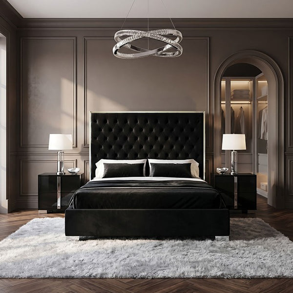 Vasiko Contemporary Glam Chrome Black Fabric Bed A luxury black upholstered bed with a tall tufted headboard, styled in a modern bedroom with dark gray paneled walls, matching nightstands, a white shag rug, and a silver ring chandelier.