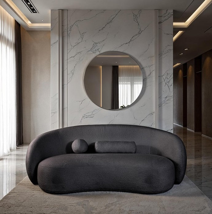 Vika Sofa Curved Back and Arm Black Modern gray sofa in a stylish room with marble walls and a round mirror.