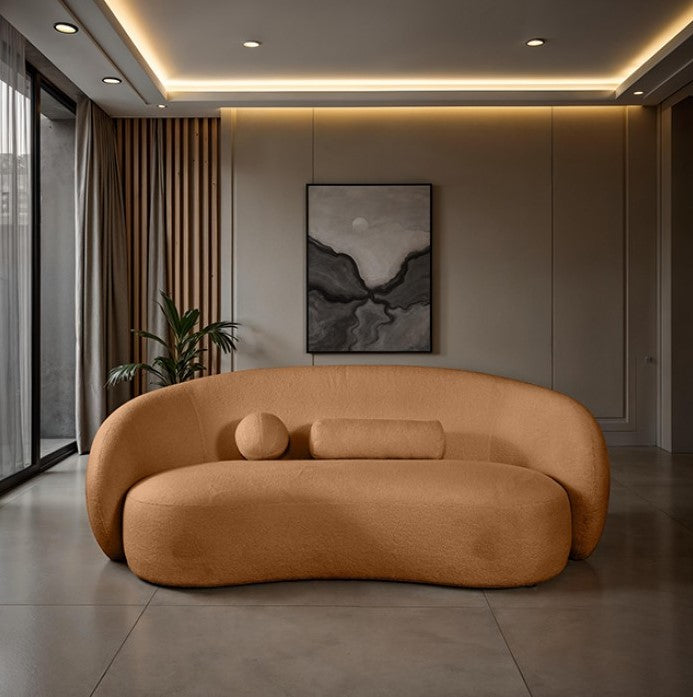 Vika Sofa Curved Back and Arm Terracotta Brown Brown curved sofa in a room with a plant and wall art.