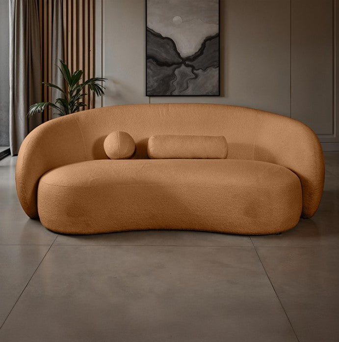Vika Sofa Curved Back and Arm Terracotta Brown Brown curved sofa in a room with a plant and wall art.