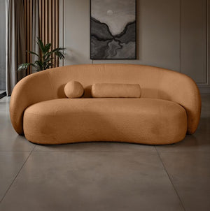 Vika Sofa Curved Back and Arm Terracotta Brown Brown curved sofa in a room with a plant and wall art.