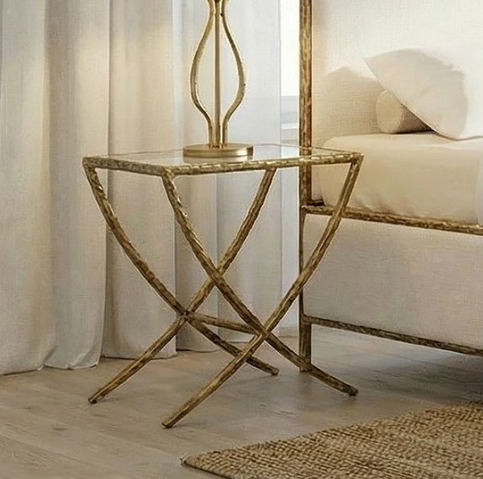 Vilber Matte Gold End Table Decorative side table with a gold finish next to a bed in a bedroom setting.