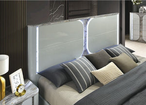 Vincenzo Modern High Gloss Finish LED Bed Modern bedroom setup with a bed featuring gray and beige pillows, a nightstand, and decorative elements.