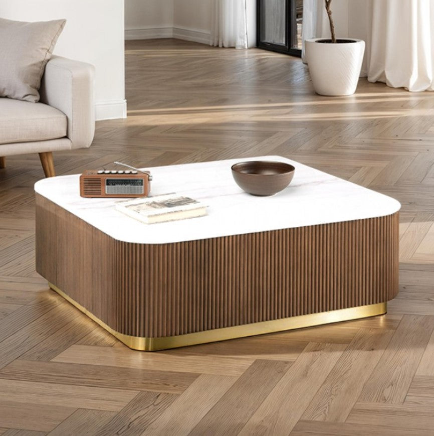 Modern coffee table with a white top and wooden base in a living room setting.