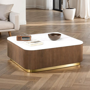Modern coffee table with a white top and wooden base in a living room setting.